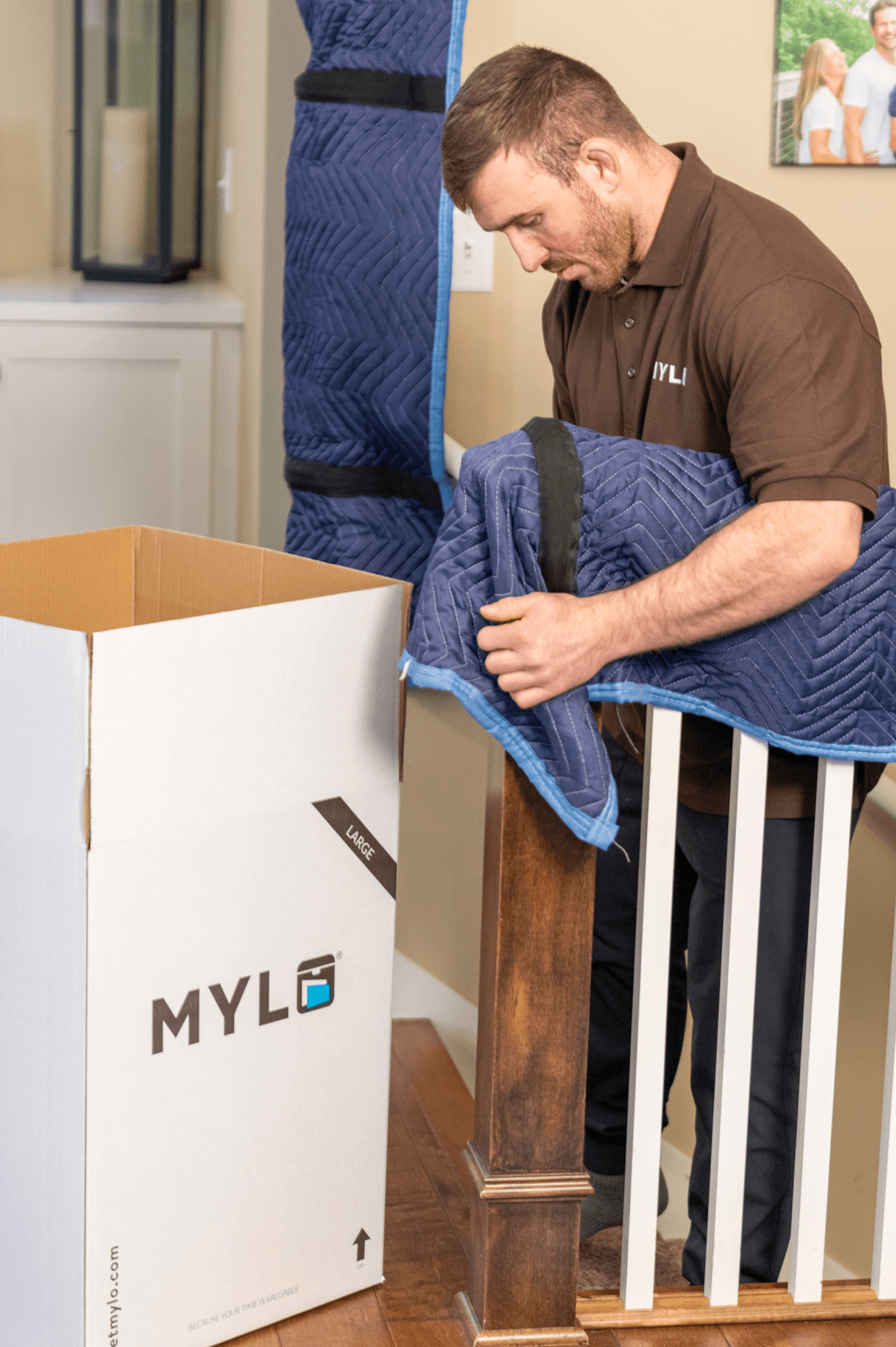 MYLO mover padding a staircase banister with a moving blanket