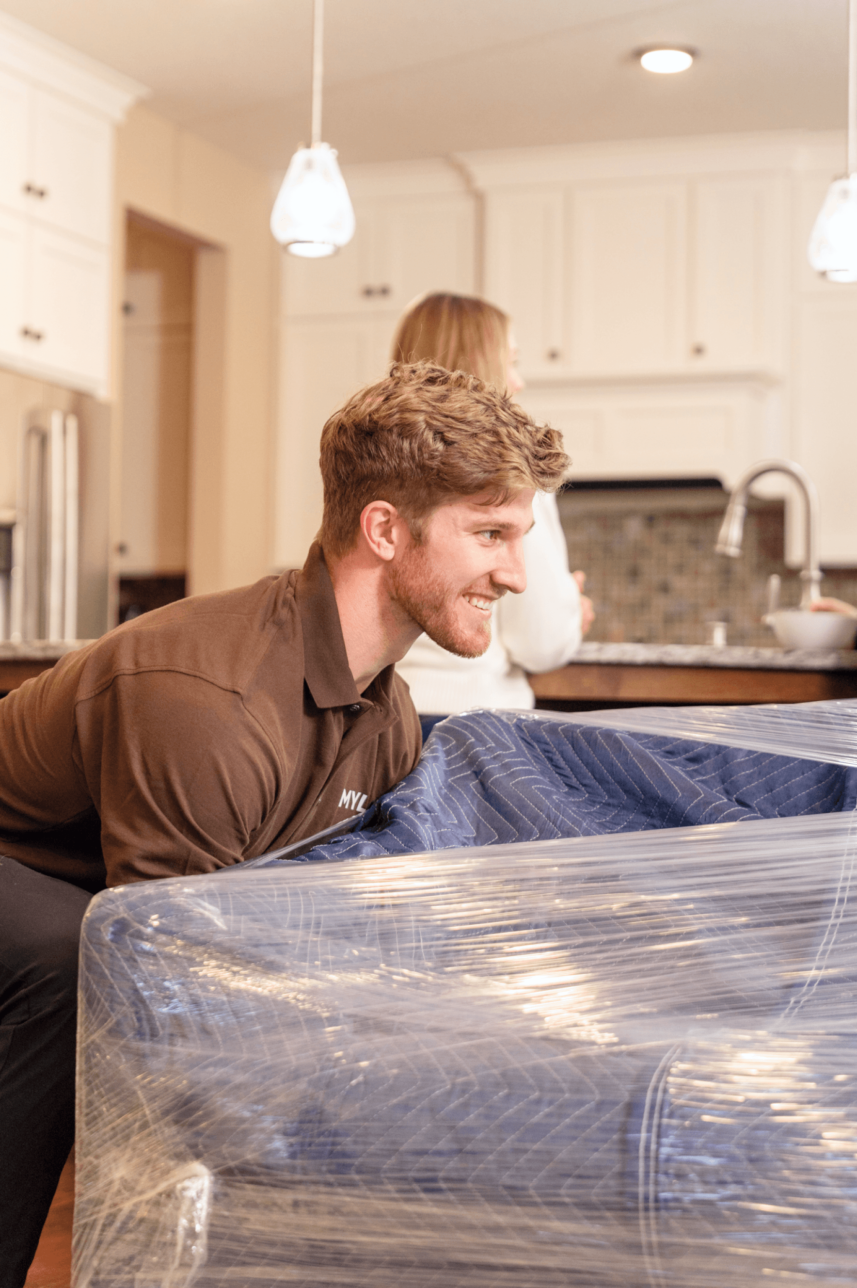 MYLO mover lifting a padded, plastic-wrapped piece of furniture